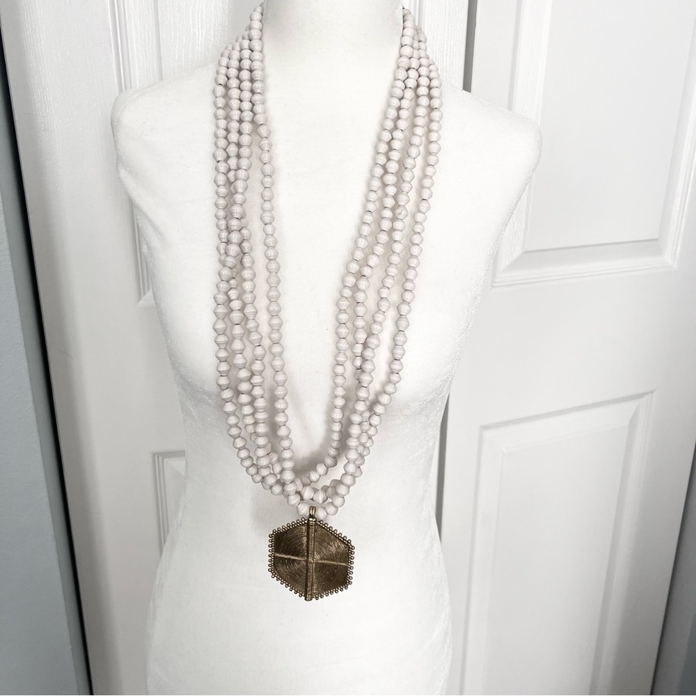 Multistrand white beaded African inspired gold tone pendant t-clasp necklace